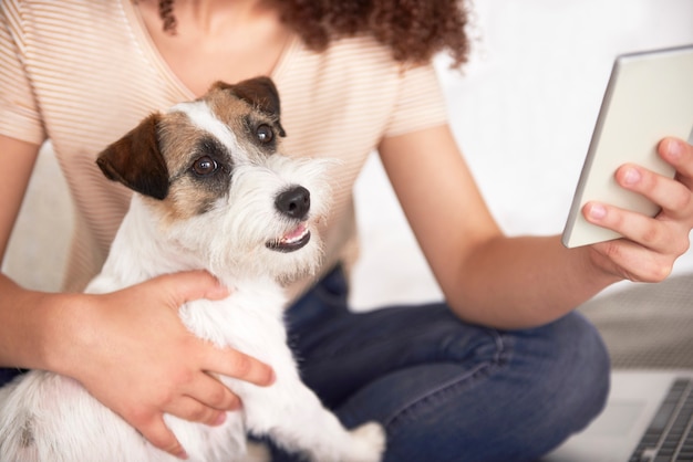 Parte della donna che abbraccia il suo cane e usa il cellulare