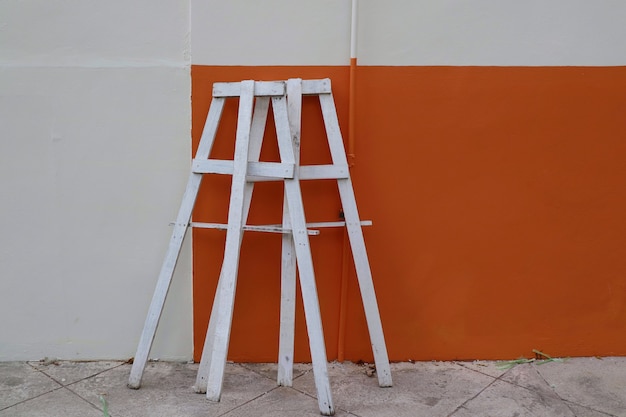 Parte della panca per impalcature in legno con parete arancione e bianca in cantiere Oggetto industriale