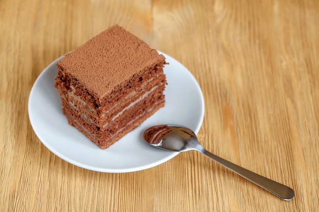 Parte della torta di cioccolato in zolla bianca sulla tabella di legno