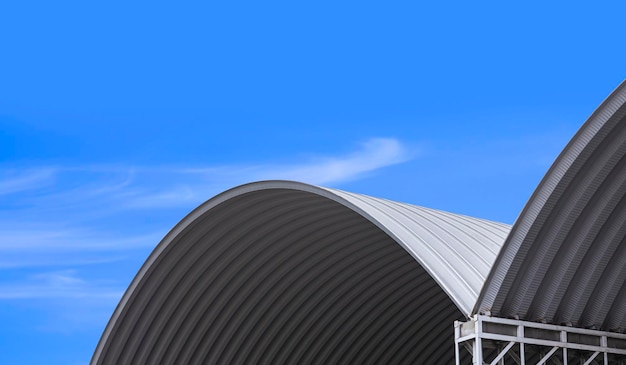 Parte di 2 grandi tetti in acciaio ondulato sullo sfondo del cielo blu, vista ad angolo basso con spazio per la copia