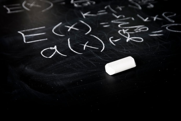 Parte di formule matematiche scritte con il gesso bianco sullo sfondo della lavagna