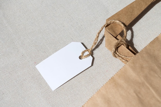 Parte di un pacchetto Kraft in cartone con un'etichetta bianca su una corda con maniglie per consegna o regalo