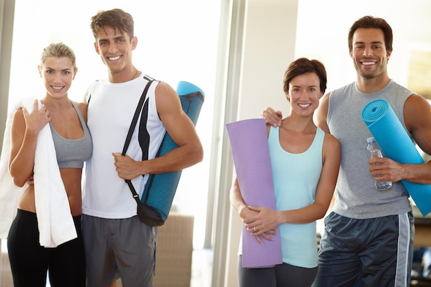 Parte di una squadra di fitness Ritratto di quattro giovani adulti che sorridono alla telecamera con la loro attrezzatura da yoga