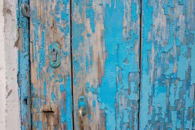 Parte di una vecchia porta di legno con peeling vernice blu e un buco della serratura