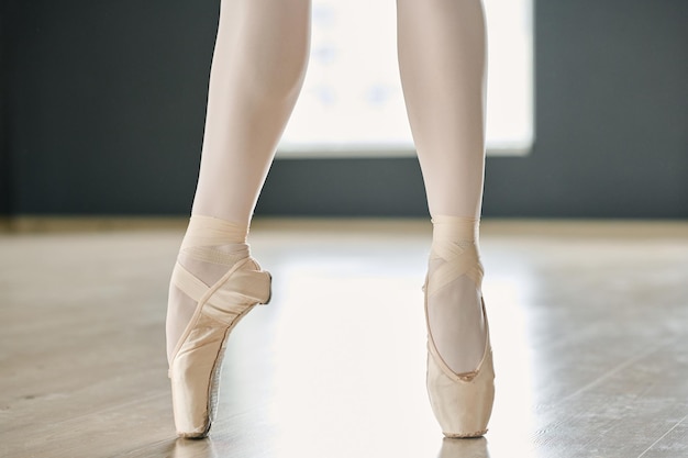 Parte inferiore delle gambe sottili della giovane ballerina in calzamaglia bianca e scarpe da punta