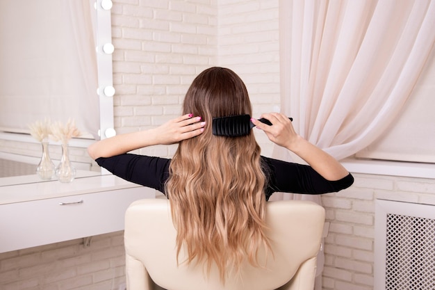 Parte posteriore della femmina con capelli castani lunghi ricci nel salone di parrucchiere