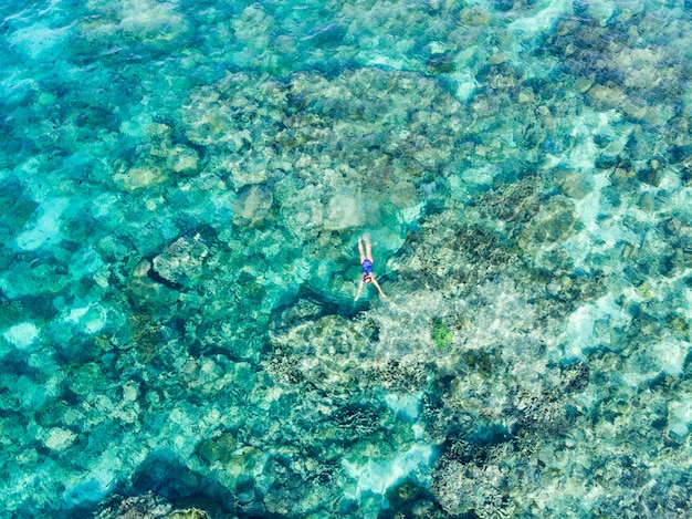 Parte superiore aerea giù la gente che si immerge sul mare caraibico tropicale della barriera corallina