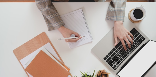 Parte superiore della donna di affari che scrive sul computer portatile e che scrive la sua idea