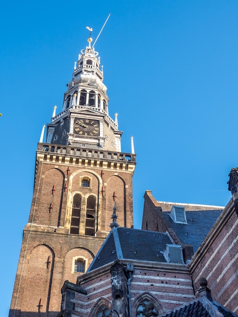 Parte superiore della vecchia chiesa (Oude Kerk) nel principale quartiere a luci rosse di Amsterdam, Paesi Bassi, sotto il cielo blu