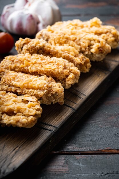 Parti di ali di pollo fritte su fondo di legno scuro.