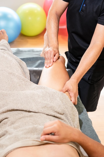 Particolare del massaggio terapeutico della coscia e dell'osteopatia di recupero sportivo Sportivo che riceve un massaggio da un fisioterapista su una barella