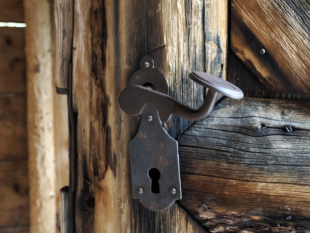 Particolare della maniglia del ferro della porta di legno della vecchia baita di montagna