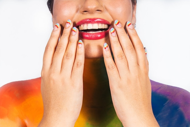Particolare delle mani che mostrano le unghie di una bella ragazza dipinta nei colori dell'arcobaleno.