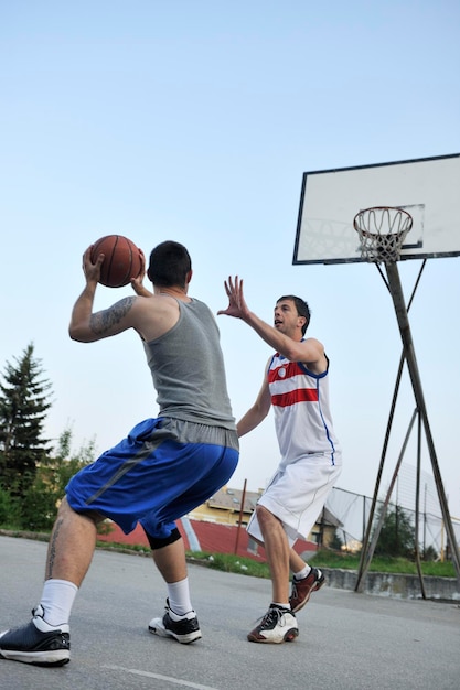partita di basket di streetball con due giovani giocatori al mattino presto sul campo cittadino