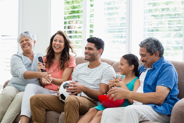 Partita di calcio di sorveglianza della famiglia di diverse generazioni felice sulla televisione in salone
