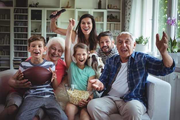 Partita di calcio di sorveglianza della famiglia felice sulla televisione in salone