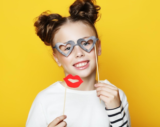 Partito infanzia e concetto di persone bambina con accessori di carta su sfondo giallo