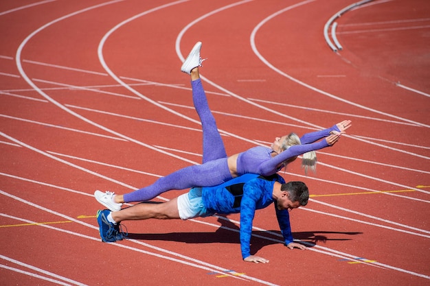 Partner di fitness che spingono verso l'alto. uomo atletico e donna sexy in tavola di supporto. allenatore maschile e femminile sull'arena dello stadio. uno stile di vita sano. forza e potenza. coppia sportiva che si allena insieme.