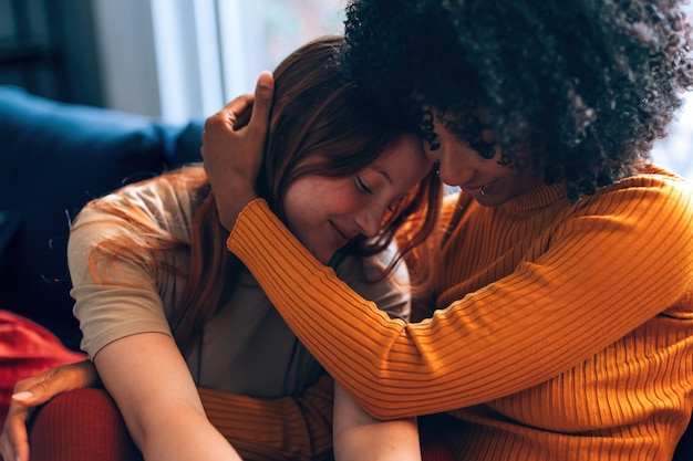 Partner femminili multietnici in armonia che si legano con tenero affetto e abbracci a casa