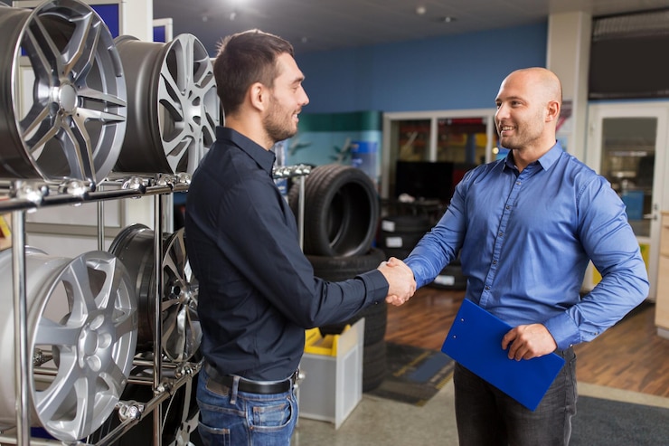 Foto partnership aziendale e concetto di persone cliente maschio e venditore che si stringono la mano in un servizio di riparazione auto o in un negozio di automobili