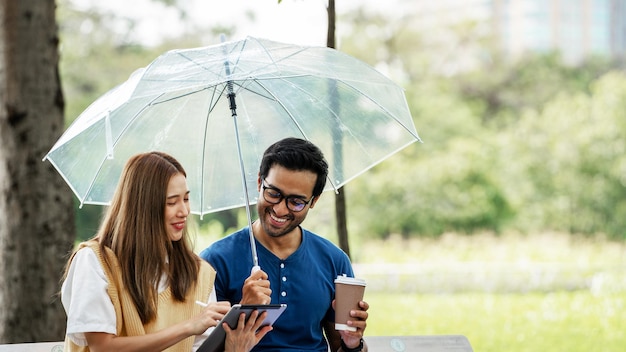 Partnership Studente Amico che tiene l'ombrello e studio di lavoro con il supporto del partner insieme al Park Business Young Couple Partner Discutere all'aperto Business Colleagues Outside Office Una coppia