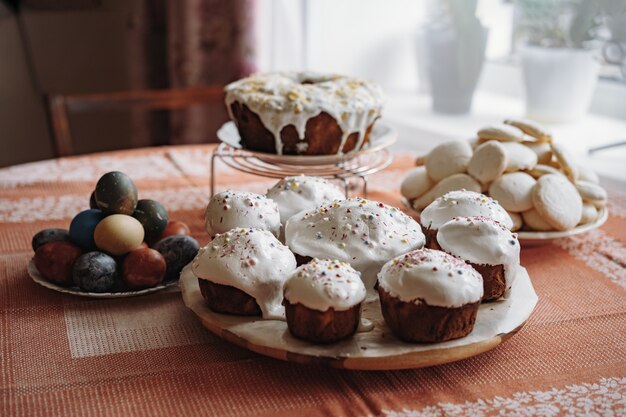 Pasqua fresca con torte ricoperte di zucchero su un piatto grande Uova colorate su sfondo