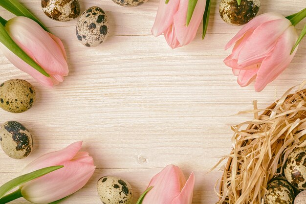 Pasqua sfondo rosa tulipani sul tavolo in legno uova di quaglia nido