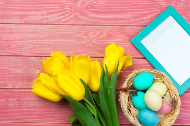 Pasqua Struttura di legno con le uova di Pasqua e i tulipani su variopinto