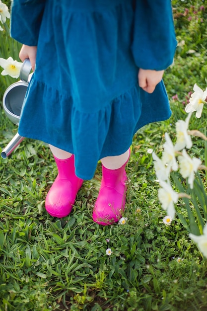 Pasqua Una bambina carina di 5 anni con orecchie di coniglio innaffia i narcisi sul prato Bambino felice Vacanze primaverili