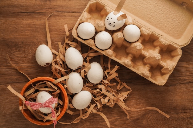 Pasqua, uovo legato con nastro rosso in ciotola di legno, uovo dipinto come faccia di coniglio nel vassoio uovo sul tavolo di legno