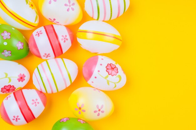 Pasqua variopinta ha dipinto le uova su colore pastello giallo con spazio.