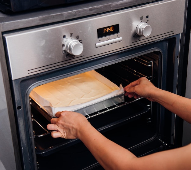 Passa la donna che tiene la torta del forno del pane della pasta sul forno anteriore