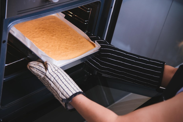 Passa la donna che tiene la torta del forno del pane della pasta sul forno anteriore