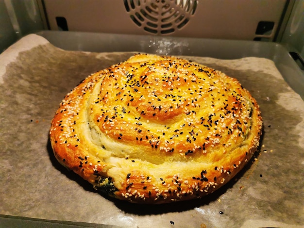 Passaggio 3 Burek con spinaci e ricotta Torta rotonda con erbe aromatiche unta con tuorlo cosparso di semi di sesamo Deliziosa torta balcanica Borek Prodotti da forno vegetariani