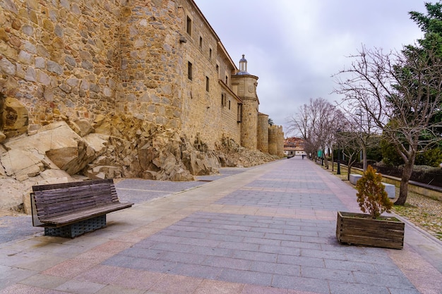 Passaggio pedonale con panchine accanto alle mura medievali della città di Avila, Spagna.