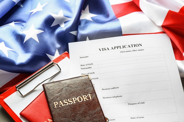 Passaporti, bandiera americana e modulo per la domanda di visto sul tavolo. Immigrazione negli USA