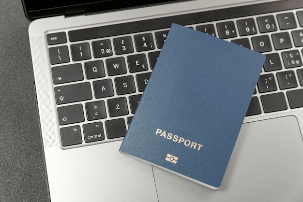 Passaporto coperto di blu sulla tastiera del laptop Copia spazio e copertina vuota Visto online Registrazione per l'immigrazione