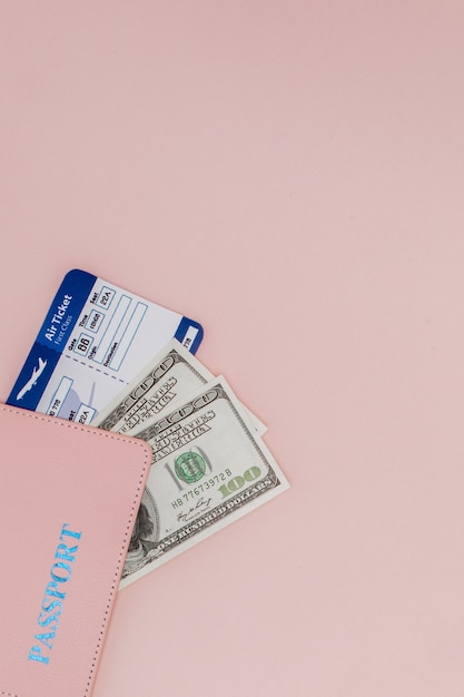 Passaporto, dollari e biglietto aereo su una superficie rosa. Concetto di viaggio, copia dello spazio.