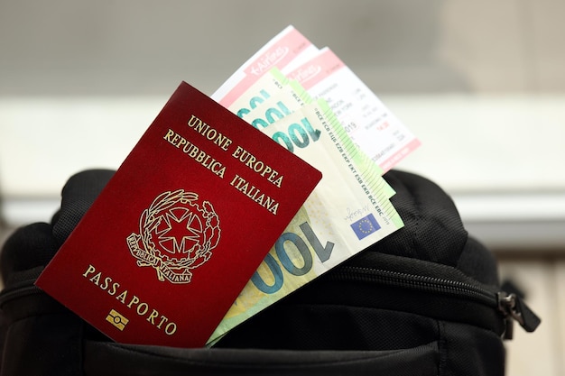 Passaporto italiano e banconote in euro con biglietti aerei sullo zaino da vicino