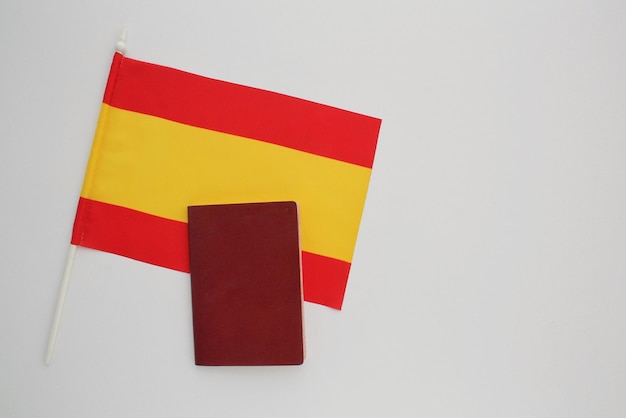 Passaporto nazionale e bandiera della Spagna su sfondo bianco. Immigrazione, profugo, cambio di cittadinanza