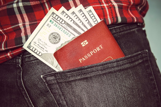 Passaporto nella tasca posteriore dei jeans con dollari americani. concetto di viaggio. paghetta nella mia tasca posteriore. spese vive. centinaia di dollari