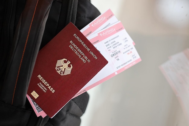 Passaporto tedesco rosso dell'Unione europea con biglietti aerei su zaino turistico