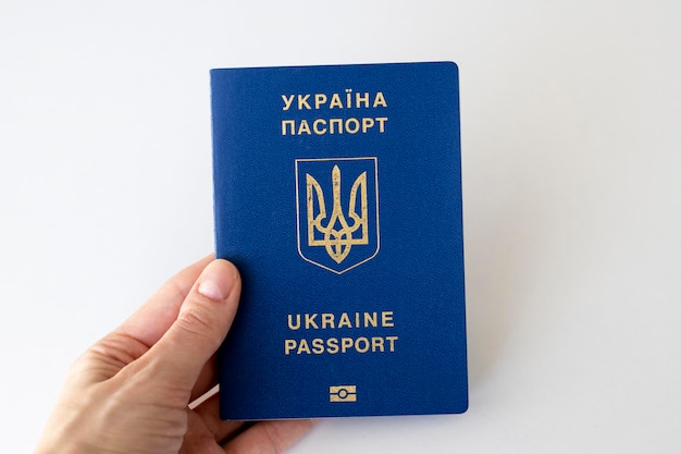 Passaporto ucraino in mano a una donna su sfondo bianco