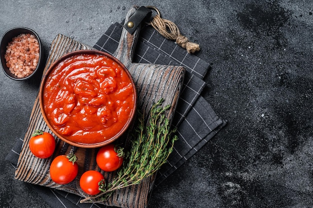 Passata di pomodoro - salsa tradizionale per la cucina italiana. Sfondo nero. Vista dall'alto. Copia spazio.