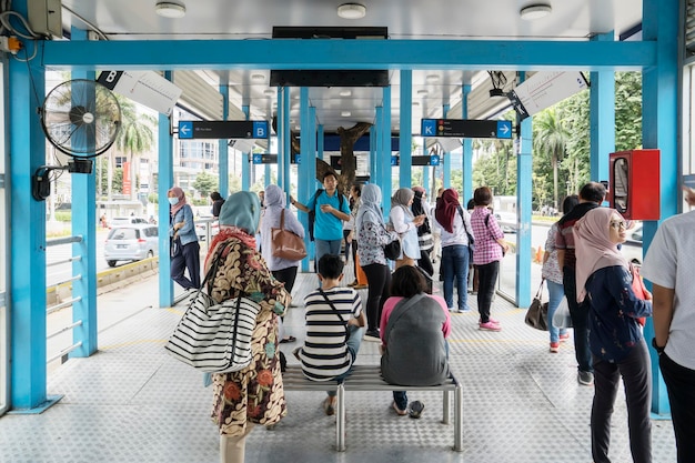 Passeggeri affollati aspettano l'arrivo dell'autobus di Transjakarta