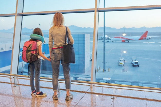 Passeggeri dell'aeroporto famiglia madre e figlia che guardano gli aerei nella finestra panoramica