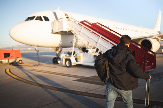 Passeggero che cammina con le sue valigie verso l'aereo