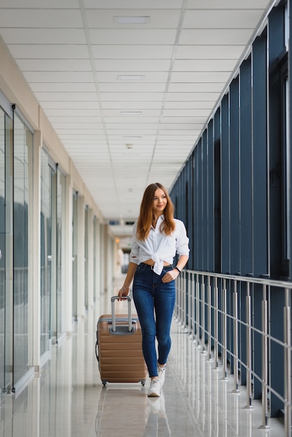 Passeggero femminile abbastanza giovane all'aeroporto (DOF poco profondo; immagine dai toni di colore)