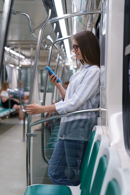 Passeggero giovane donna che utilizza smartphone mobile in chat nei social network in treno della metropolitana a metro