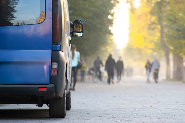 Passeggero van automobile parcheggiata su un vicolo della città sul lato della strada con pedoni a piedi offuscati in autunno.